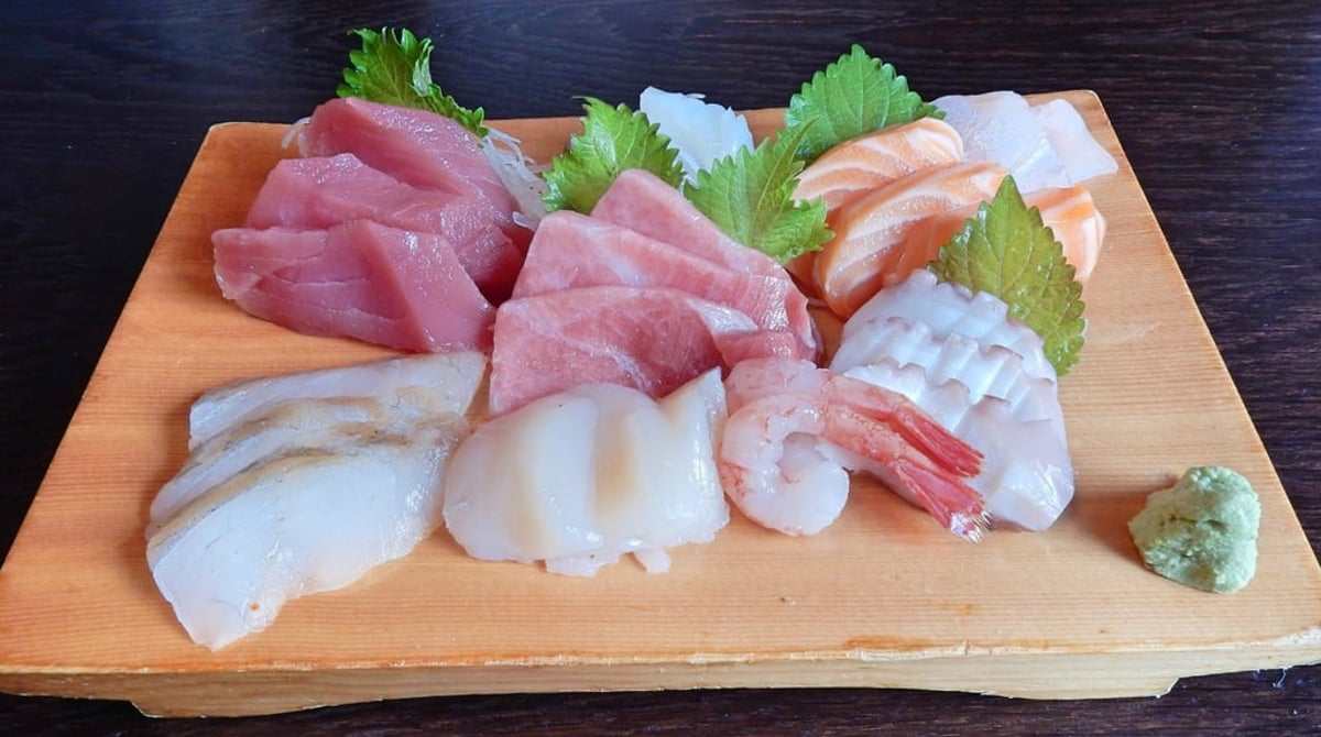 Sashimi-Platte mit Thunfisch, Lachs und Muscheln auf einem Holzbrett