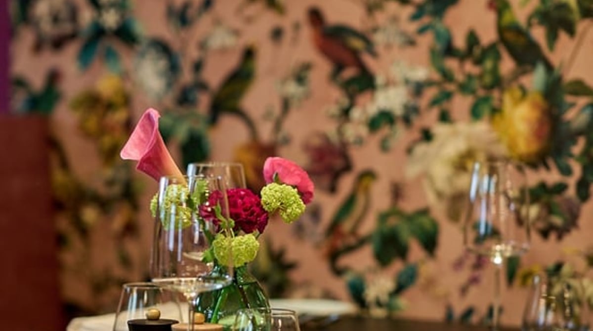 Gedeckter Tisch vor einer Blumentapete im Restaurant