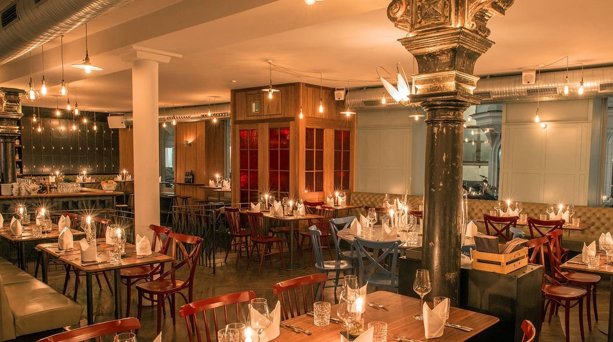 Gastraum der Burger & Lobster Bank mit gusseiserner Säule, Kerzen auf den Tischen und Holzstühlen