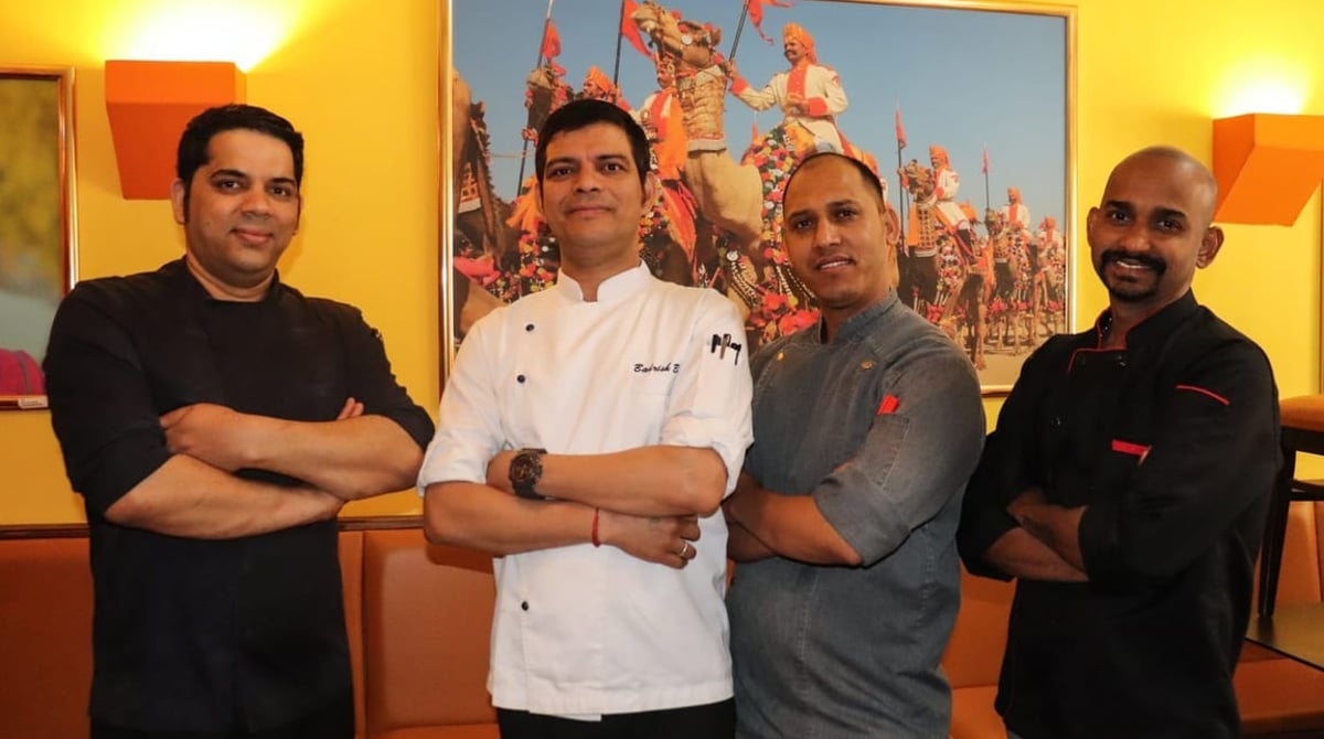 Vier Köche in weißen Jacken vor einem Wandbild im Indian Mango in München