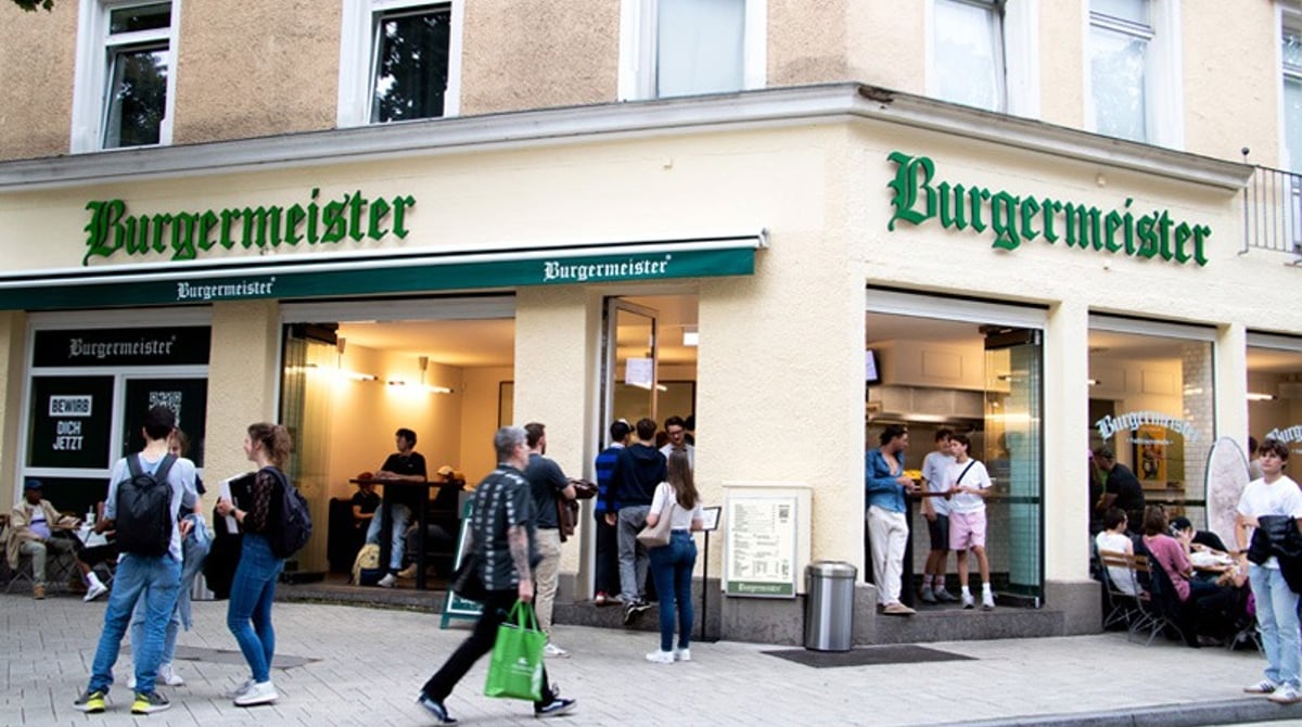 Eckhaus mit grüner Burgermeister-Markise in der Feilitzschstraße, davor Gäste auf dem Gehweg