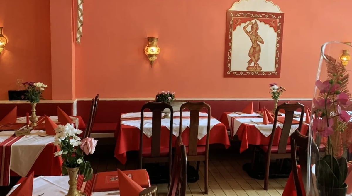 Tische mit roten Decken vor einer lachsfarbenen Wand mit Tänzerinnenbild im Ganga