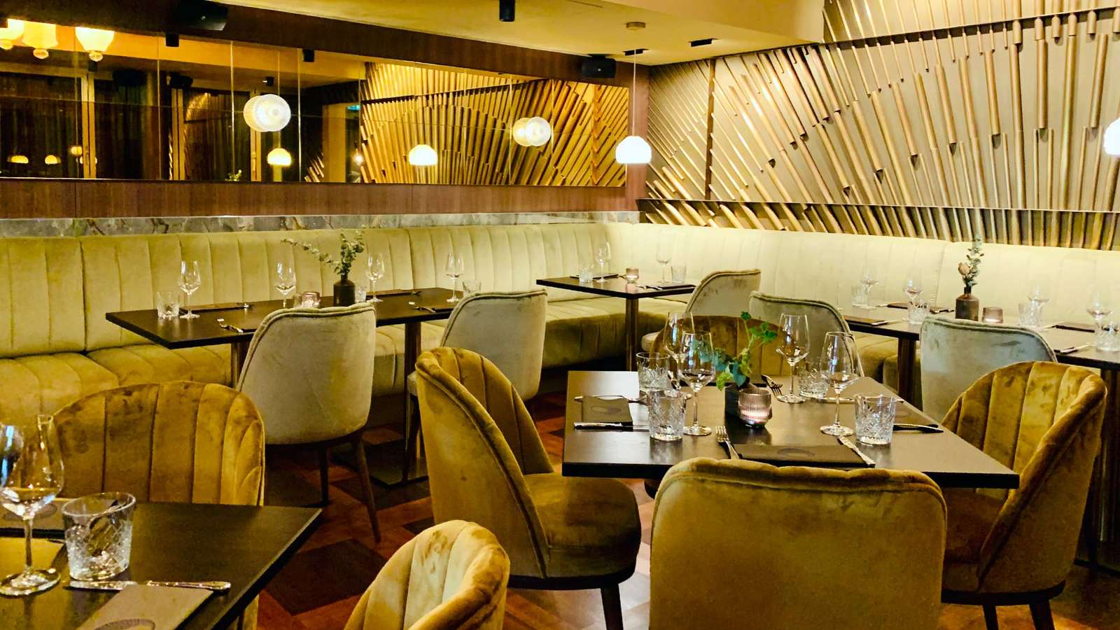 Elegantes Interieur des St. Ribs mit Eichenparkett, lindgrünen Samtbänken und senffarbenen Sesseln