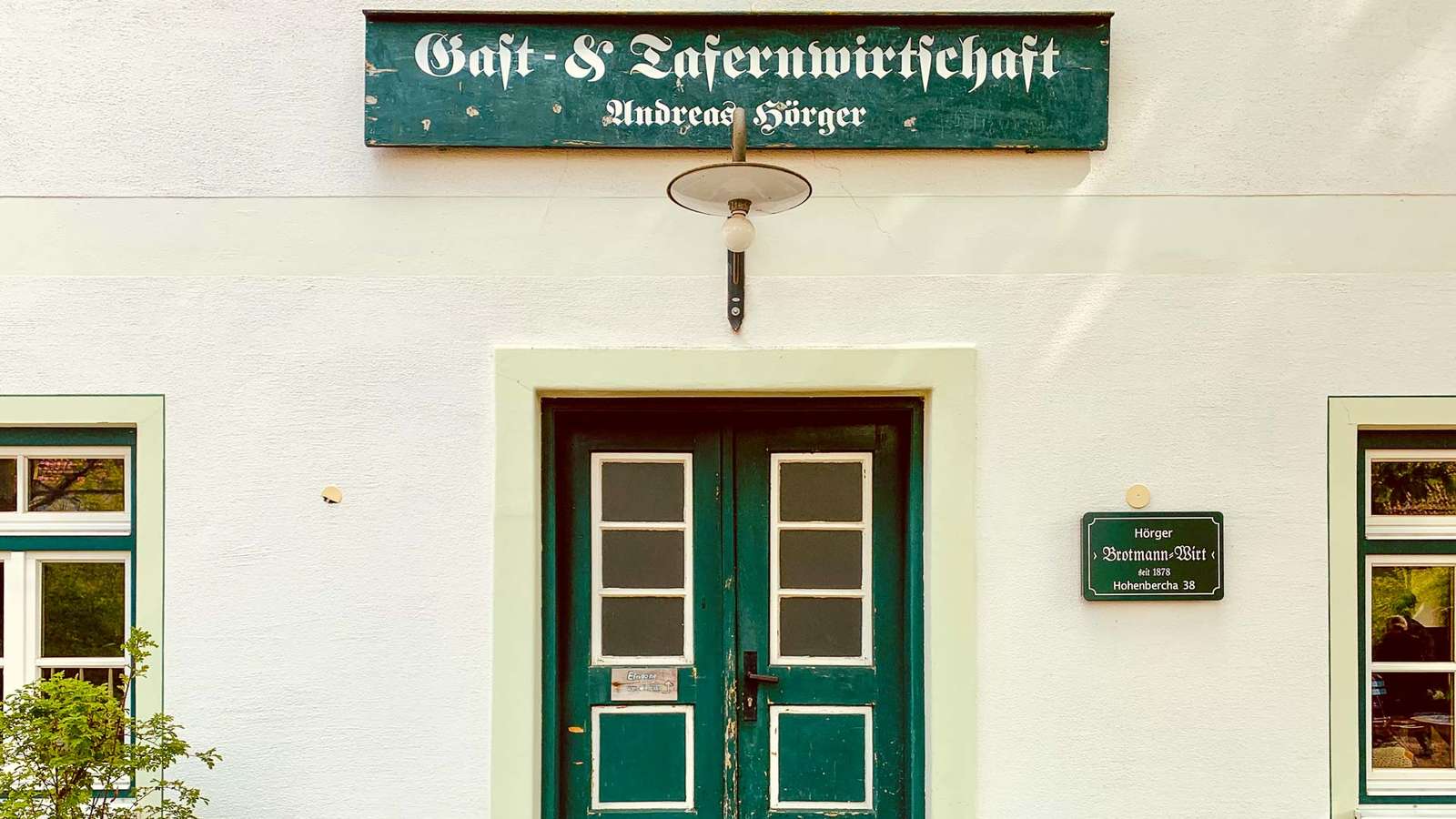 Eingang der Gast- und Tafernwirtschaft Andreas Hörger mit grüner Holztür und Schriftzug über der Tür