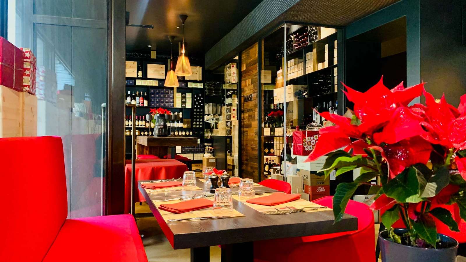 Gastraum der Masi Wine Bar mit roter Sitzbank, gedeckten Tischen und Weinregalen im Hintergrund