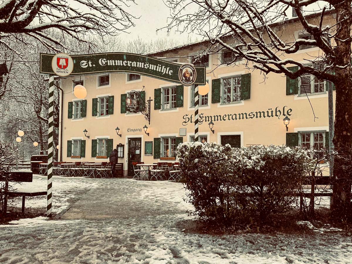 Außenansicht der Emmeramsmühle im Schnee mit Girlande und grünen Fensterläden