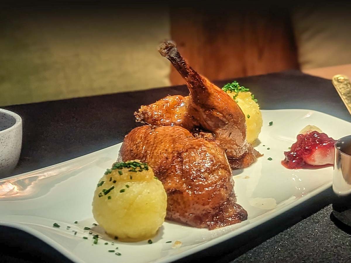 Knusprige Bauernente mit Knödel und Preiselbeeren auf einer länglichen Platte
