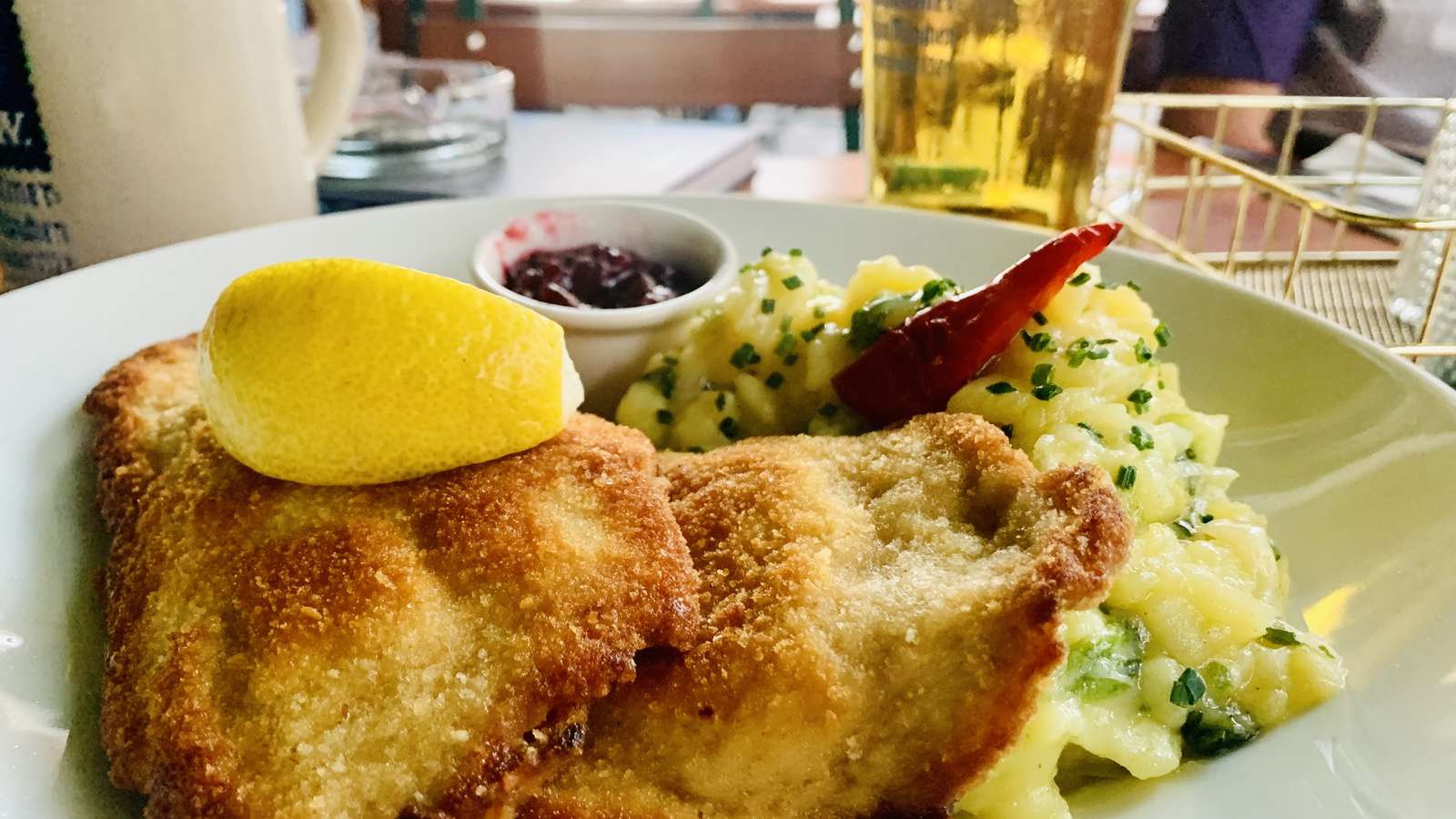 Münchner Schnitzel vom Strohschwein mit lauwarmem Kartoffel-Endiviensalat, Preiselbeeren und Zitrone im fesch