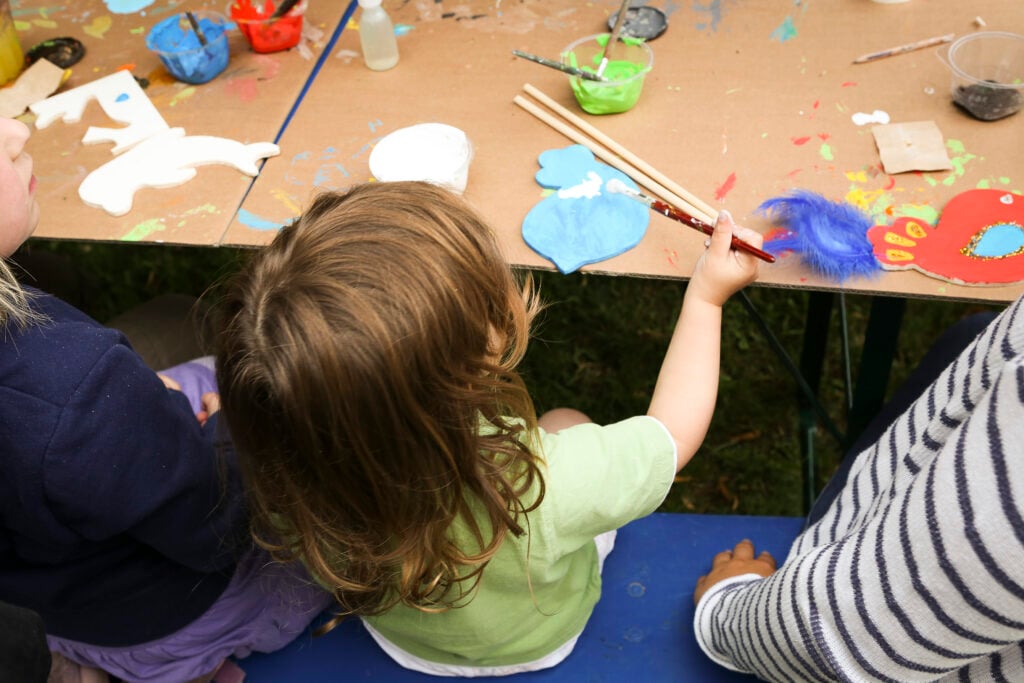 Sommerfest 2014 - IN München - Das Stadtmagazin Kind bemalt eine Holzfigur bei einem Bastelworkshop beim Dschungelpalast Sommerfest im Feierwerk München