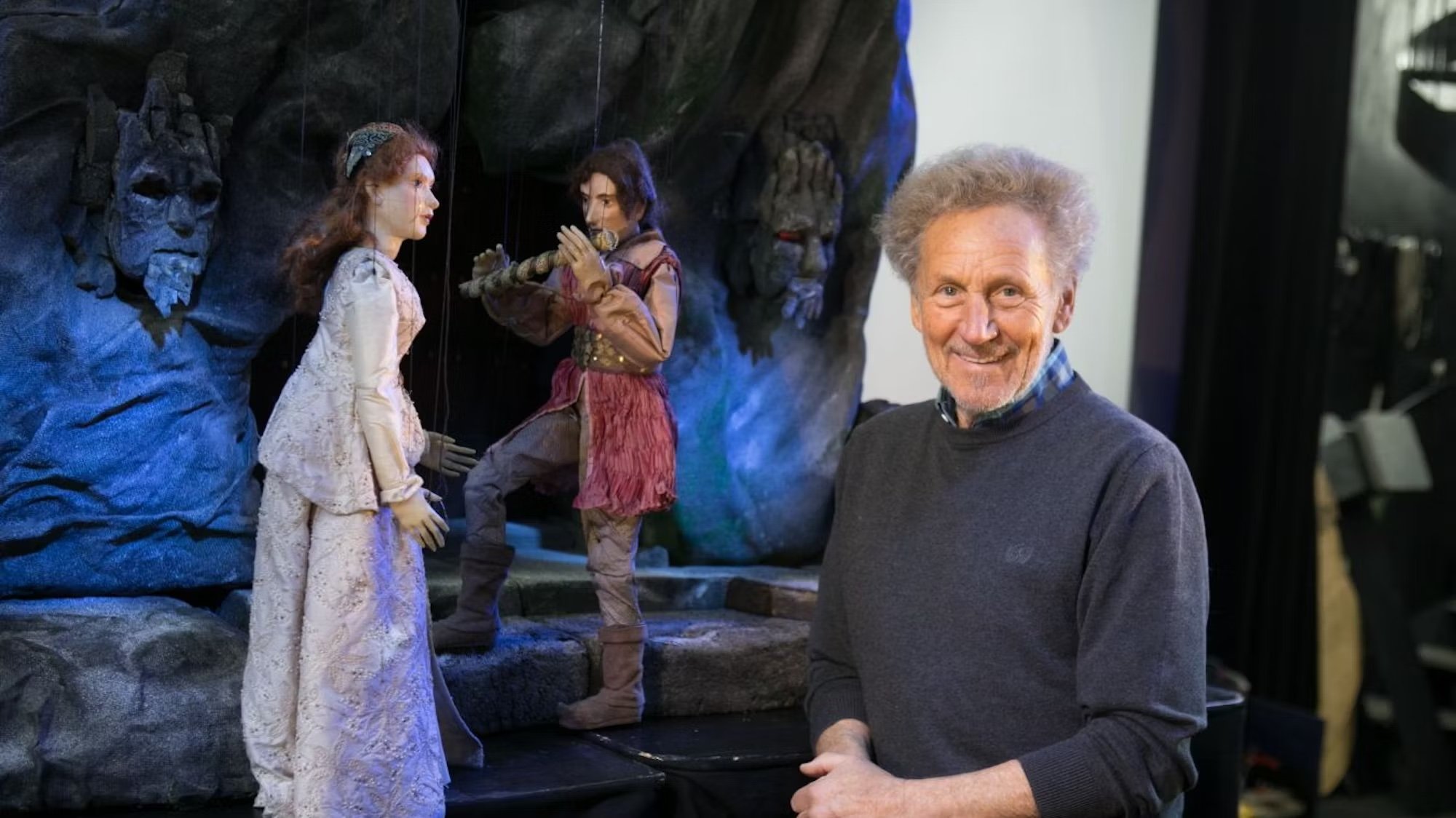 Leiter des Theaters Siegfried Böhmke neben einer Kulisse der Zauberflöte und den Puppen Tamino und Pamina.