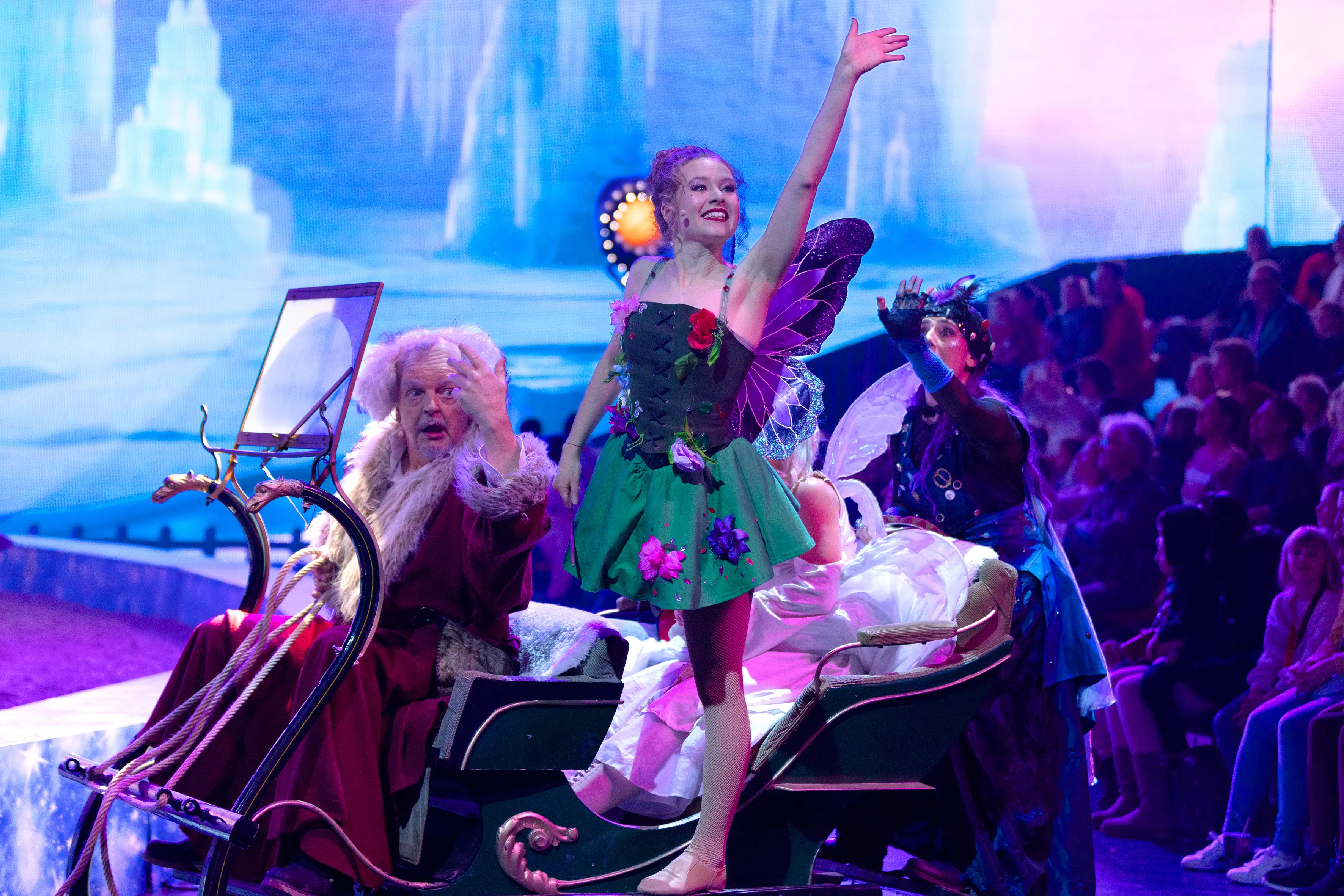 Eine Elfe winkt, sie sitzt mit dem Nikolaus in einer Kutsche