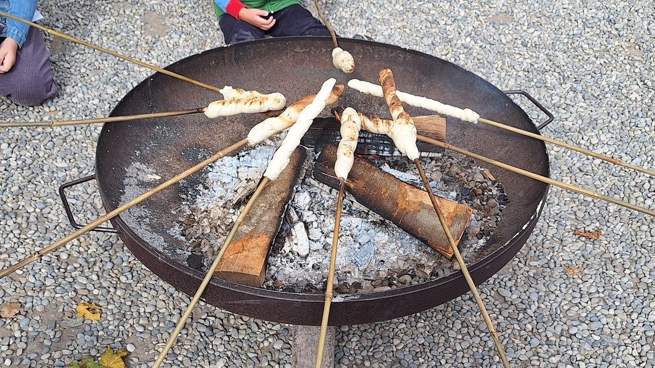 Stockbrot wird an Stöcken über eine Feuerschale gebraten