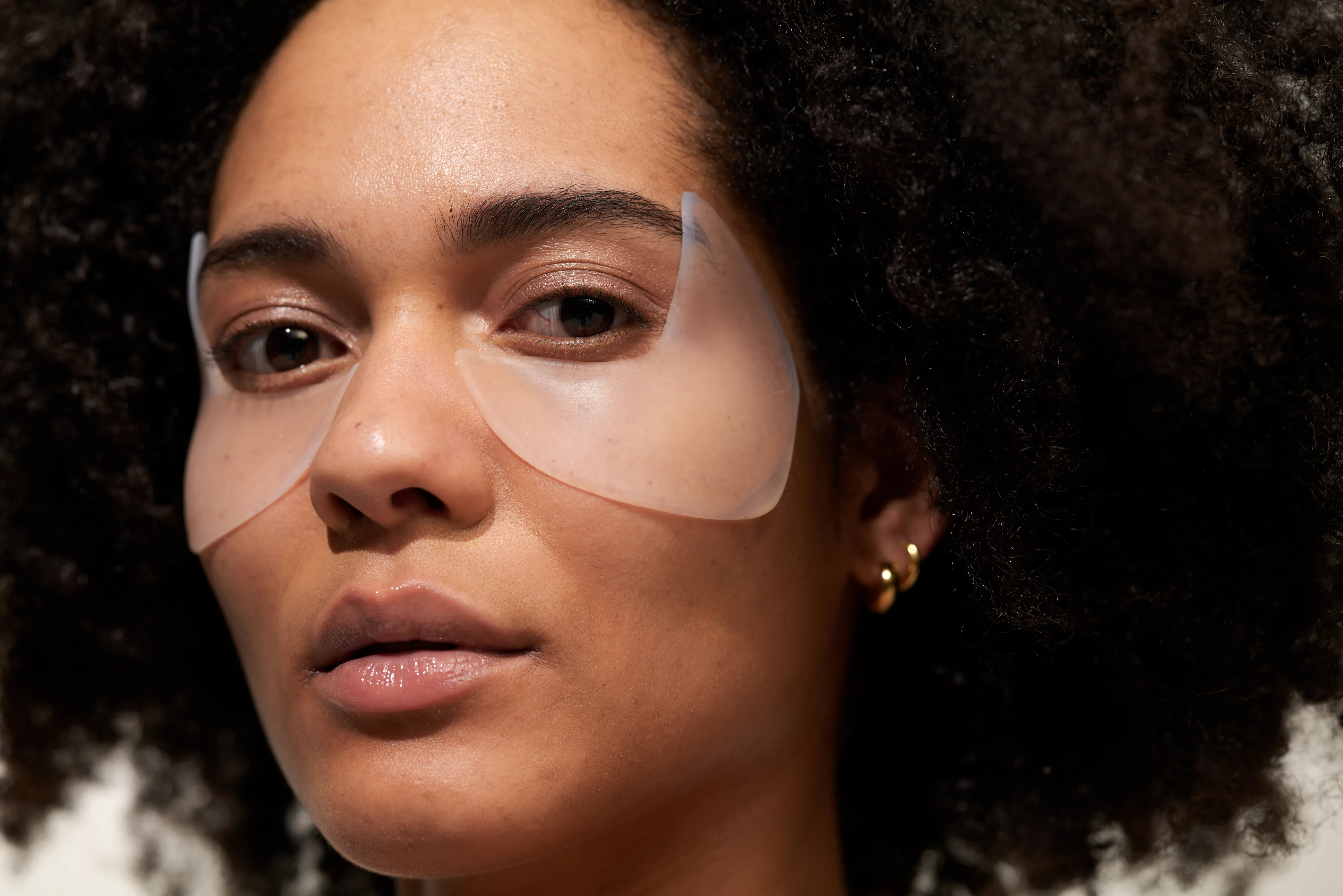 Close-up of a woman wearing a translucent face mask, showing her eyes, nose, and lips.