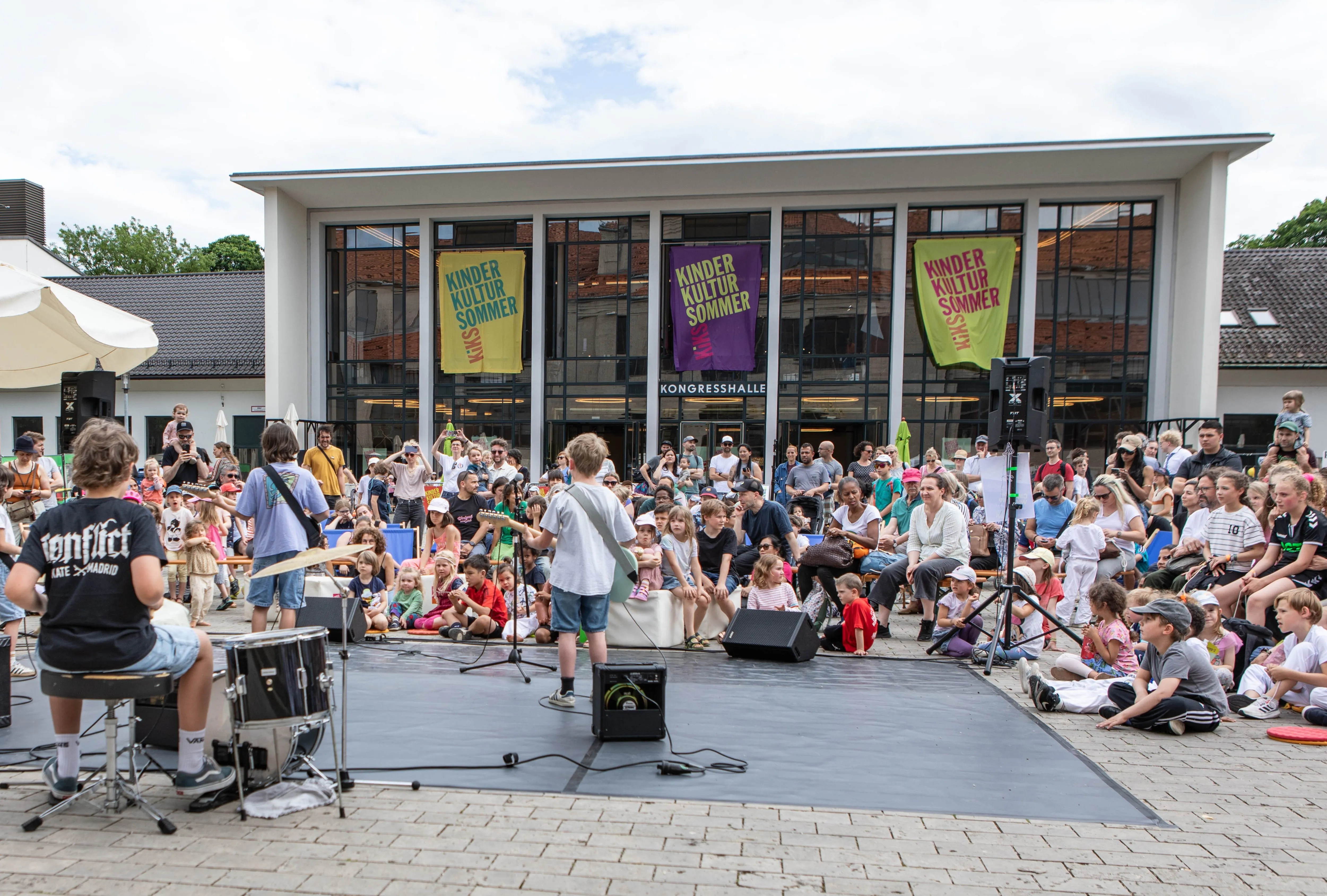 Eine Kinderband spielt bei KiKS Kinderkultursommer vor der Kongresshalle in München