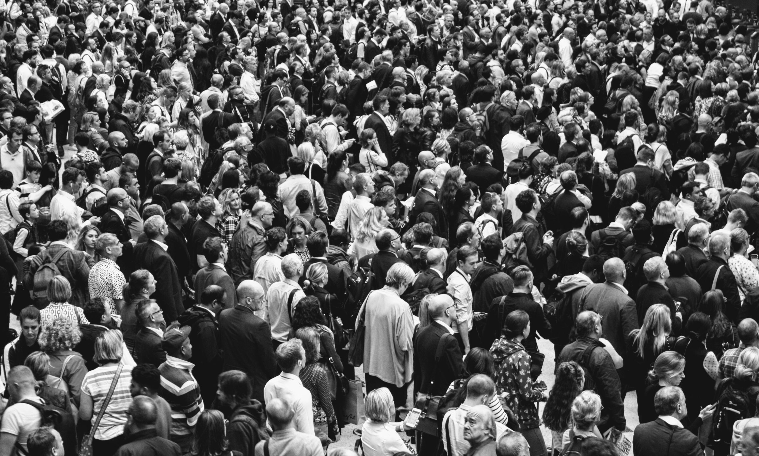 Large crowd of people walking in a busy street, seen from above; black-and-white photo.
