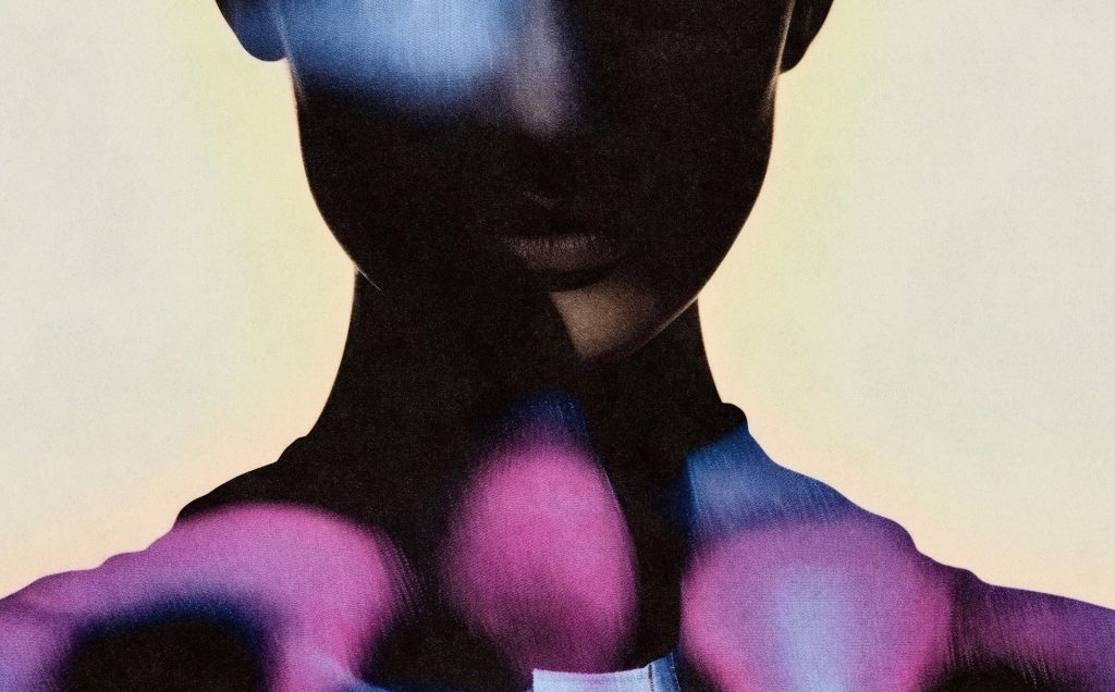 TechnoQueen_header3 - IN München - Das Stadtmagazin Close-up of a dark-skinned person's lower face and neck in an abstract image, with vivid pink, purple, and blue shapes around the collar area.