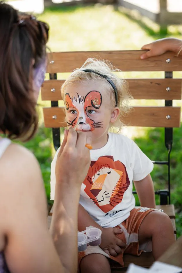 Kinderfest in Iffeldorf © Gut Aiderbichl - IN München - Das Stadtmagazin Mädchen wird zur Löwin geschminkt beim Kinderschminken auf dem Kinderfest auf Gut Aiderbichl