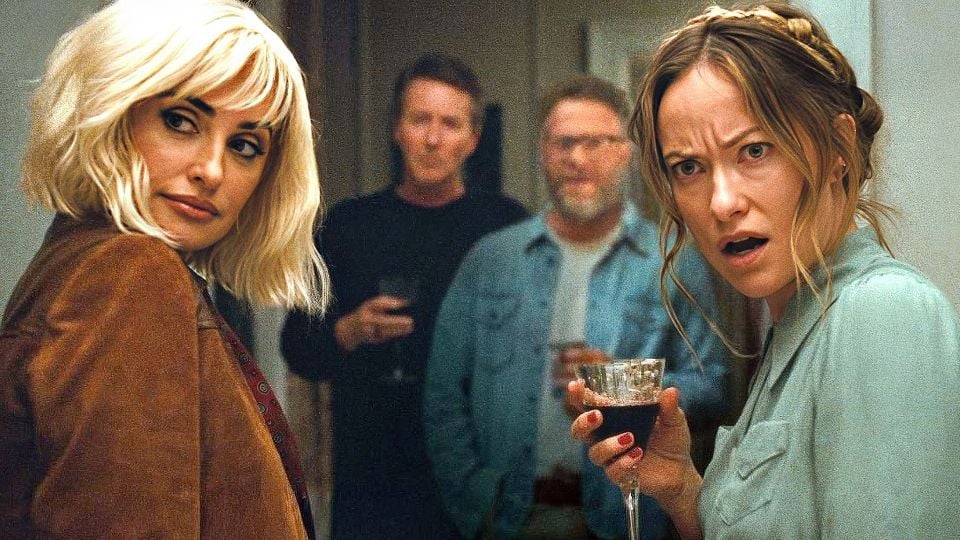 Two women in a party scene: the blonde on the left glances back, while the woman on the right holds a wine glass with a surprised expression; two men stand in the doorway behind them.