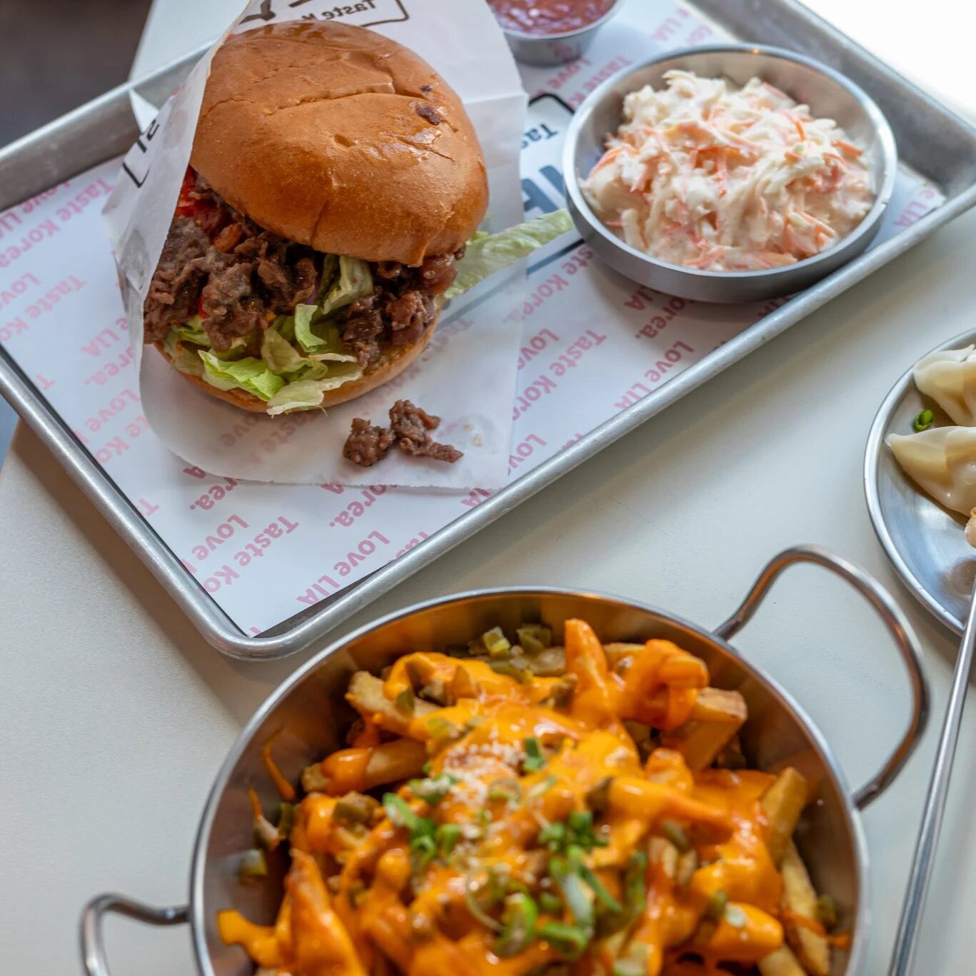 w=1367 - IN München - Das Stadtmagazin Beef burger with lettuce on a bun, served on a metal tray with coleslaw and a small cup of sauce