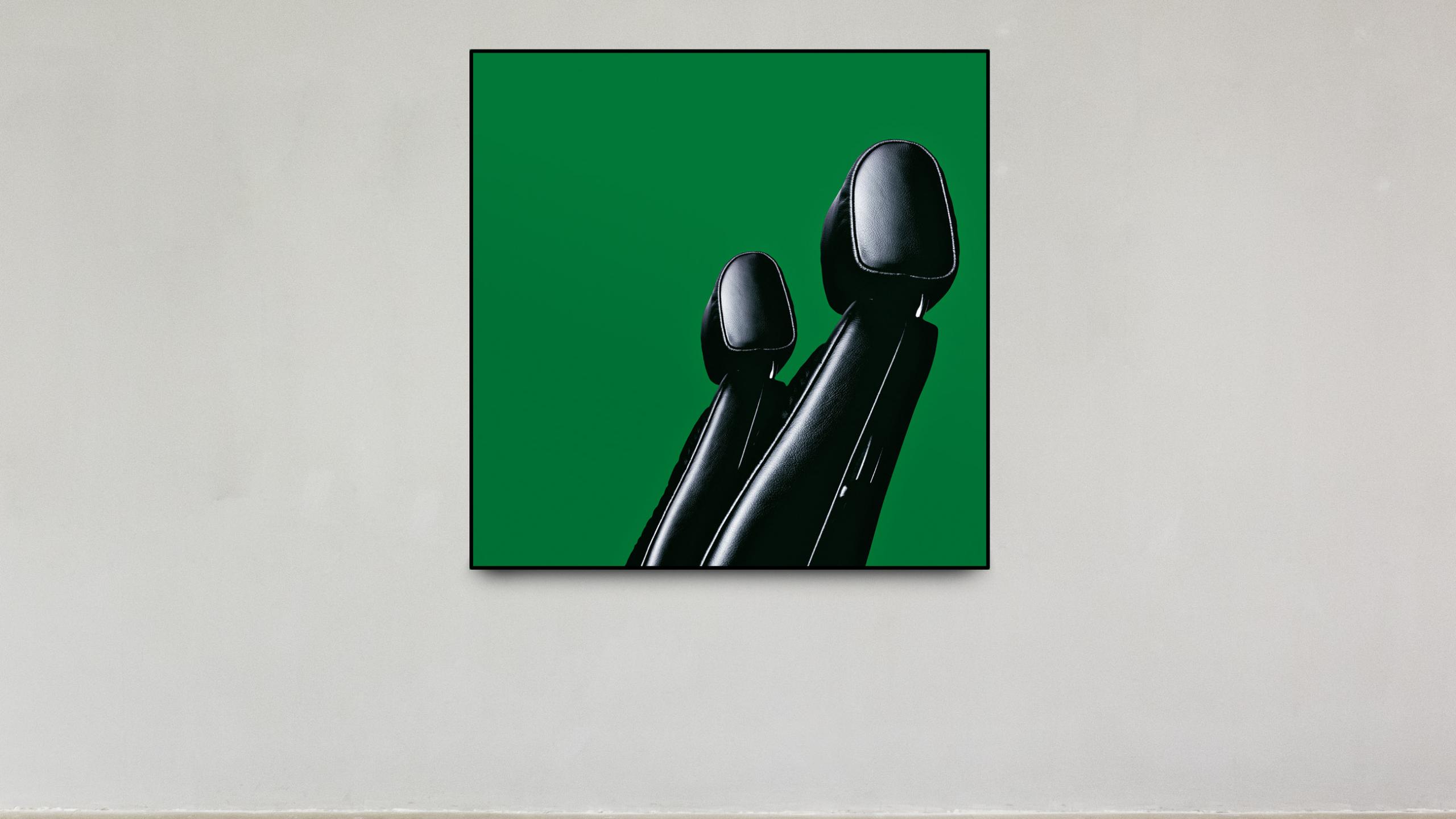 Framed green panel featuring two overlapping black leather chair cushions against a bold background.