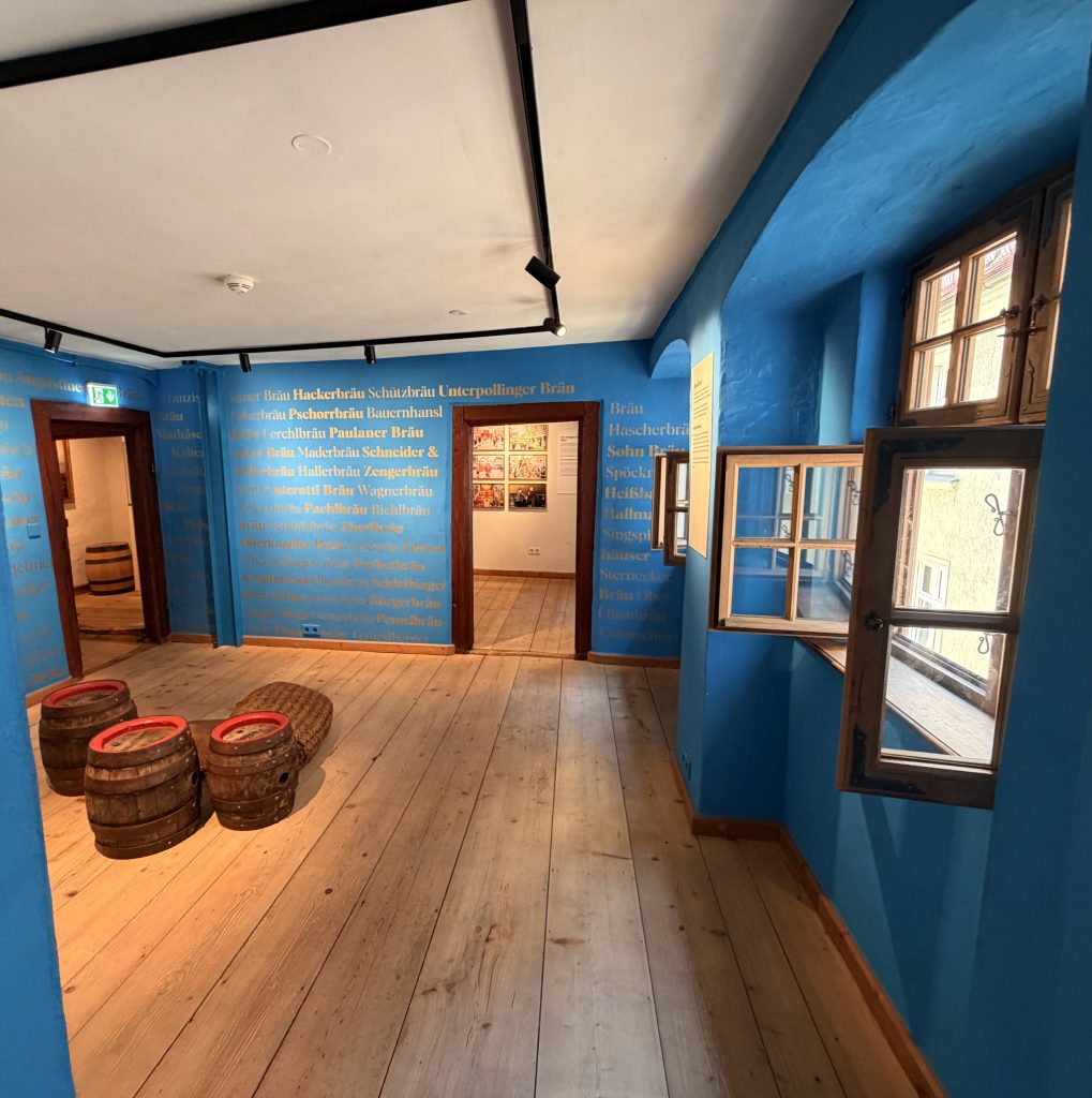 Biermuseum-muenchen-dritter-stock - IN München - Das Stadtmagazin Museumsraum im Biermuseum München mit blauen Wänden und Fässern auf dem Boden