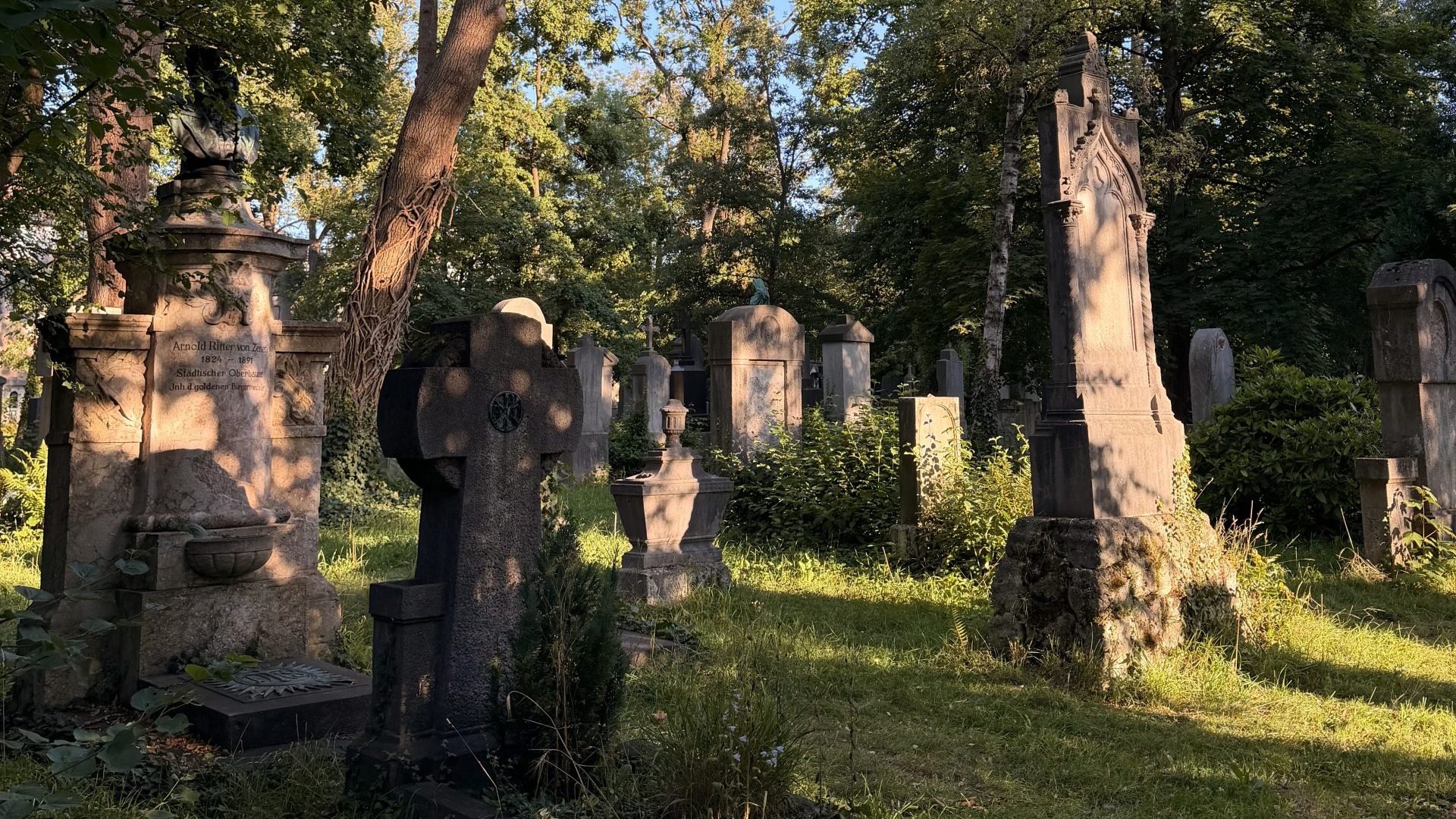 Bäume werfen Schatten auf die Gräber auf dem Alten Südfriedhof München