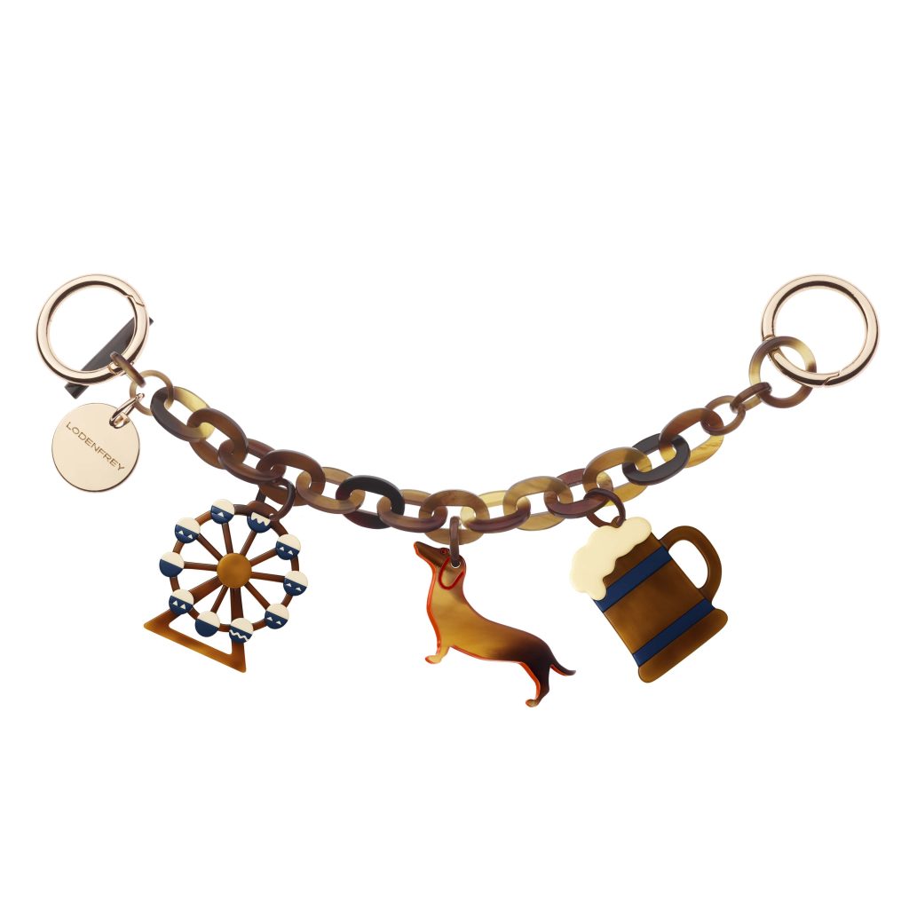 Partial view of a multi-tone chain necklace with round gold rings and a circular tag reading 'LODENFREY' at the left edge of the image.