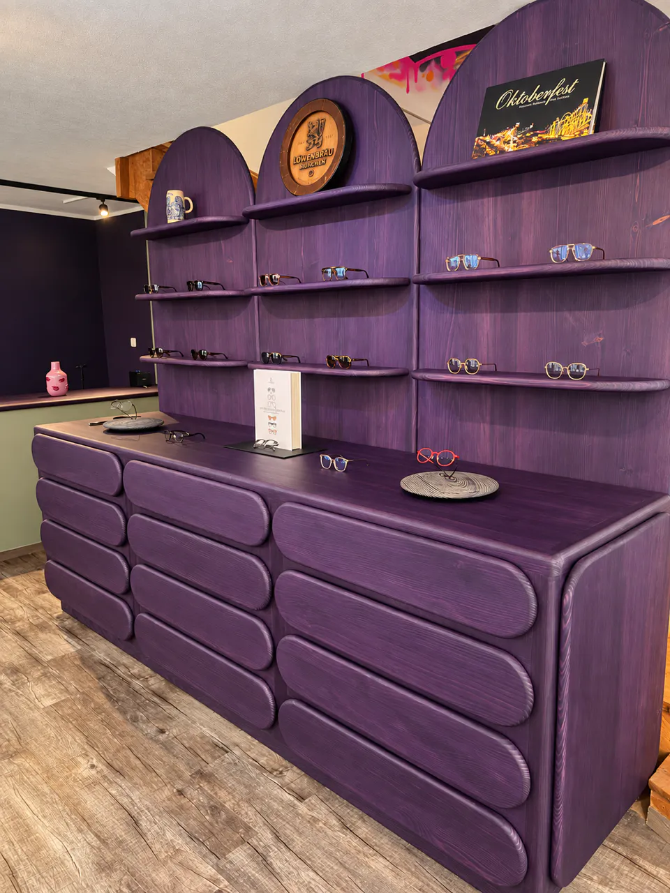 Purple wood display counter and shelves showcasing sunglasses in a boutique eyewear shop.