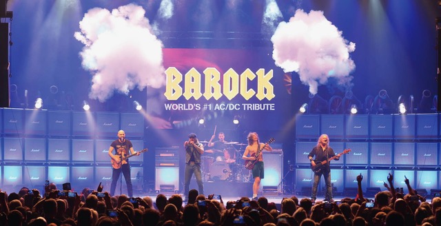 Barock_MT 1800x923 - IN München - Das Stadtmagazin Barock AC/DC tribute band performing on stage with a large BAROCK banner, blue amp walls, stage smoke, and a cheering crowd in front.
